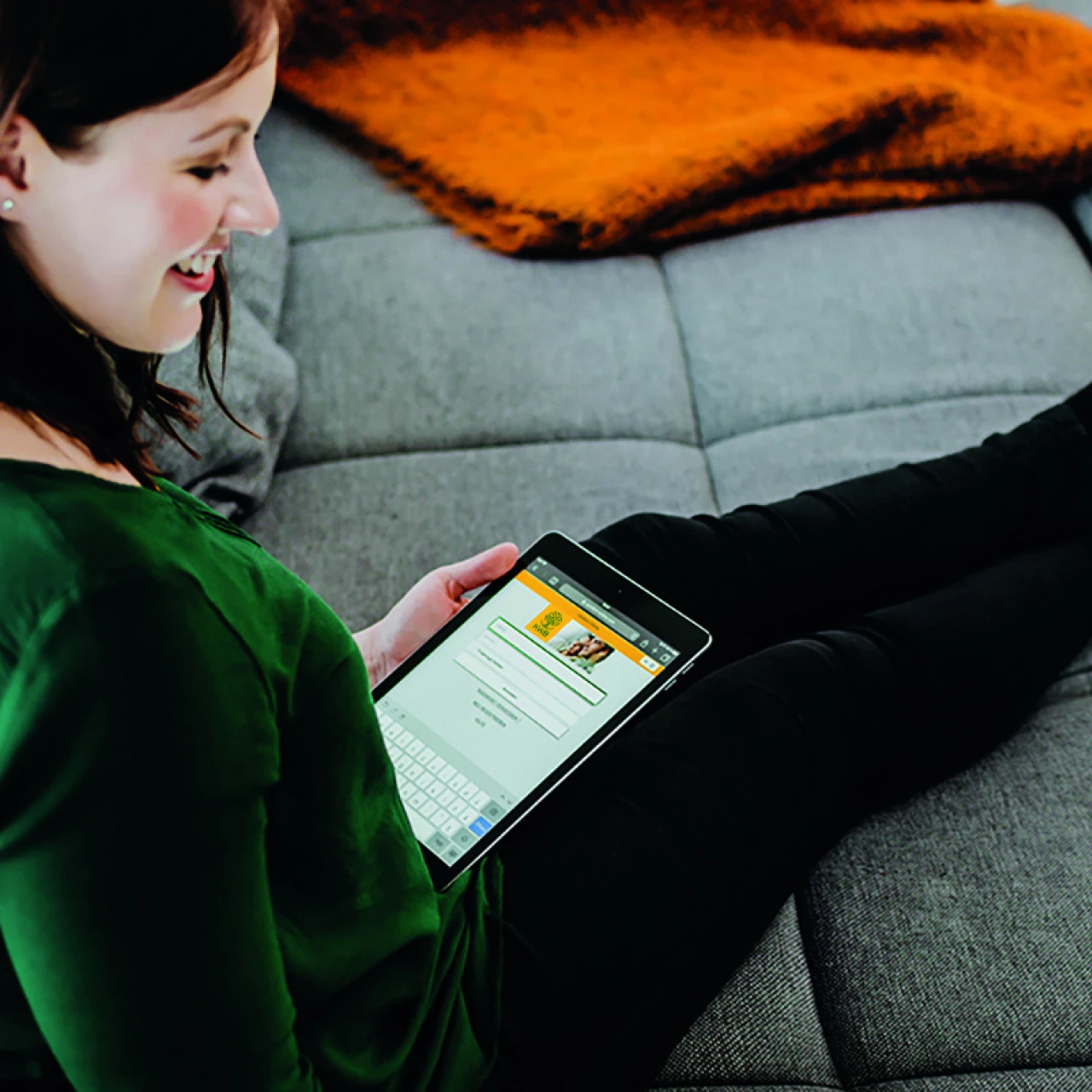 comfort online | © Lupispuma Eine Frau sitzt gemuetlich auf dem Sofa und nutzt ein Tablet