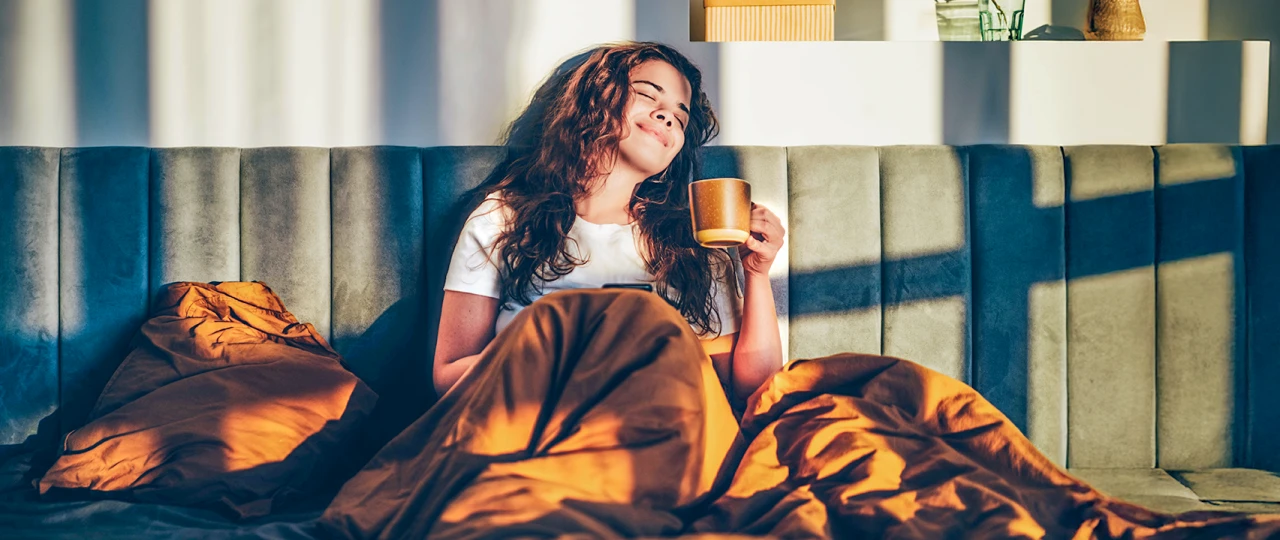 Frau entspannt | © Mariia Korneeva Eine Frau sitzt entspannte mit einer Tasse Kaffee im Bett
