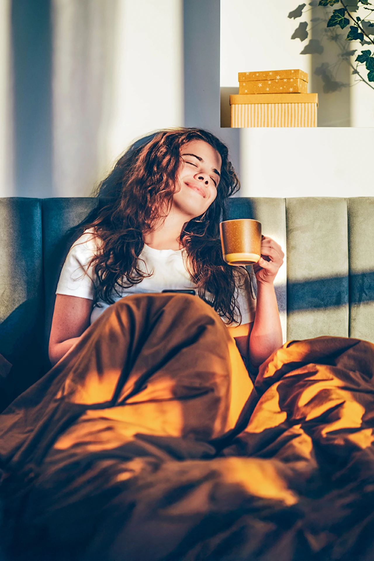 Frau entspannt | © Mariia Korneeva Eine Frau sitzt entspannte mit einer Tasse Kaffee im Bett