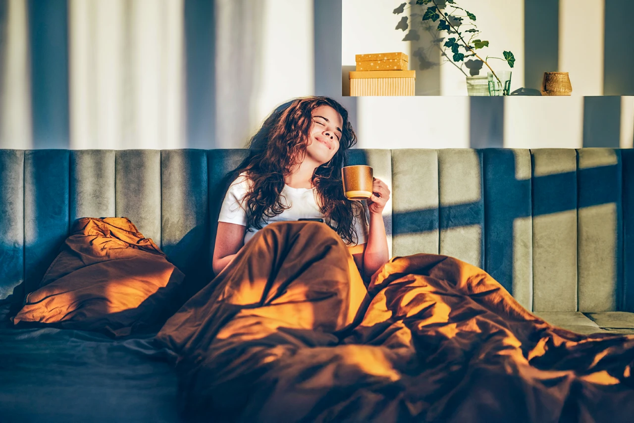 Frau entspannt | © Mariia Korneeva Eine Frau sitzt entspannte mit einer Tasse Kaffee im Bett