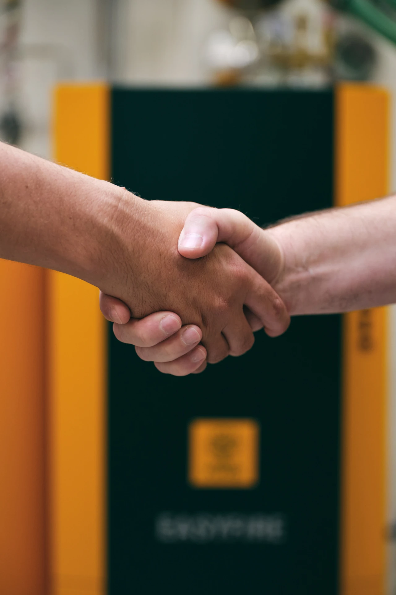 Handschlag | © KWB, Raphael Nast Nahaufnahme eines Handschlages und im Hintergrund sieht man einen KWB Kessel