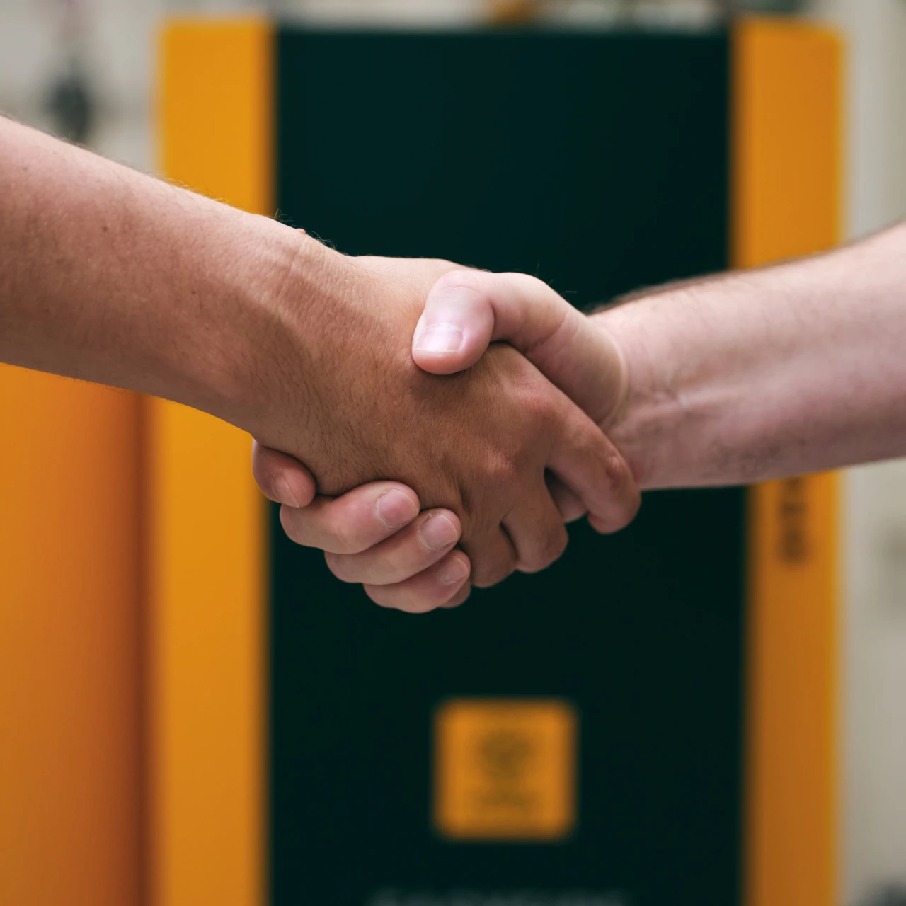 Handschlag | © KWB, Raphael Nast Nahaufnahme eines Handschlages und im Hintergrund sieht man einen KWB Kessel
