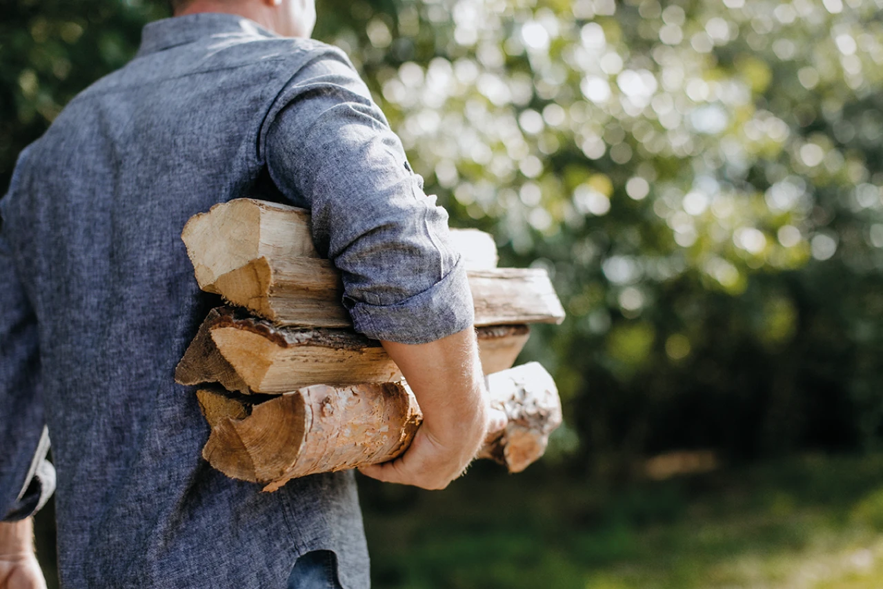 Holzscheite tragen | © KWB, LupiSpuma Ein Mann trägt in den Armen Stückholz