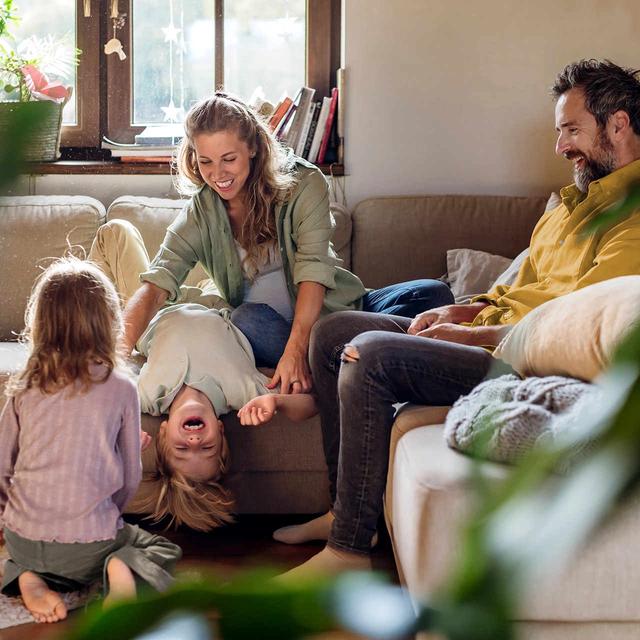 Familienzeit | © KWB, Halfpoint Eine fröhliche Familie sitzt im Wohnzimmer auf dem Sofa.