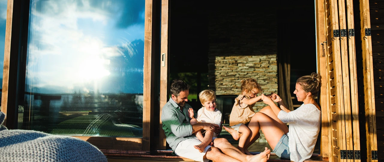 Familienzeit | © KWB, Halfpoint Familie sitzt lachend auf der Terrasse vor dem Haus und genießt die Sonne.