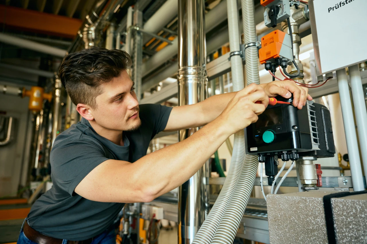 Elektrotechniker | © KWB, Raphael Nast Ein KWB Mitarbeiter mit Schraubenzieher arbeitet an einer Maschine