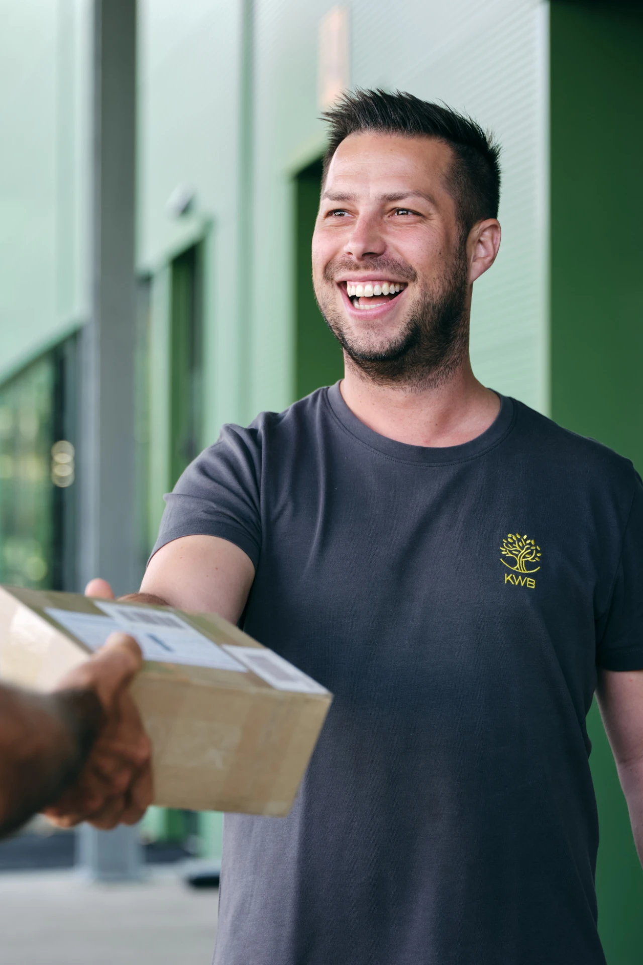 Gewährleistungsmanagement | © KWB, Raphael Nast Ein KWB Mitarbeiter nimmt laechelnd ein Paket entgegen