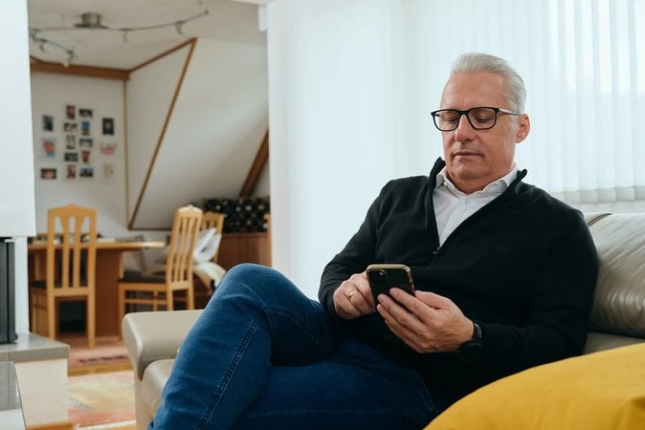 Referenzkunde Martiner | © KWB, Raphael Nast Hier sieht man Herrn Nast auf seinem Sofa und er haelt sein Handy