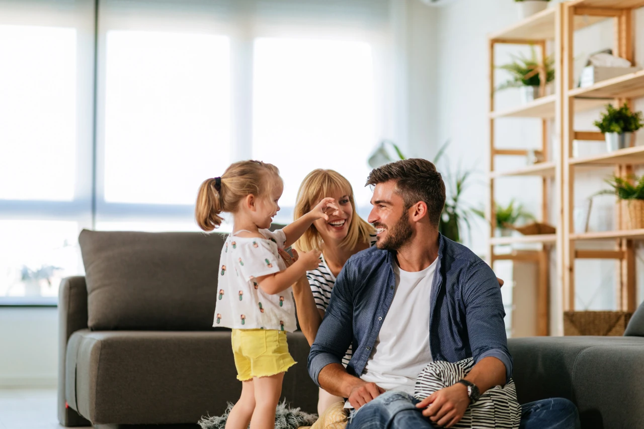 Familie | © KWB, Bernhard Bodo Mutter, Vater, Kind sitzen auf dem Wohnzimmerboden und lachen