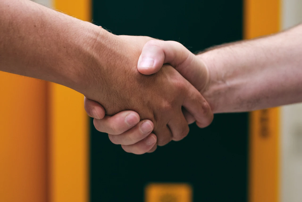 Handschlag | © KWB, Raphael Nast Nahaufnahme eines Handschlages und im Hintergrund sieht man einen KWB Kessel