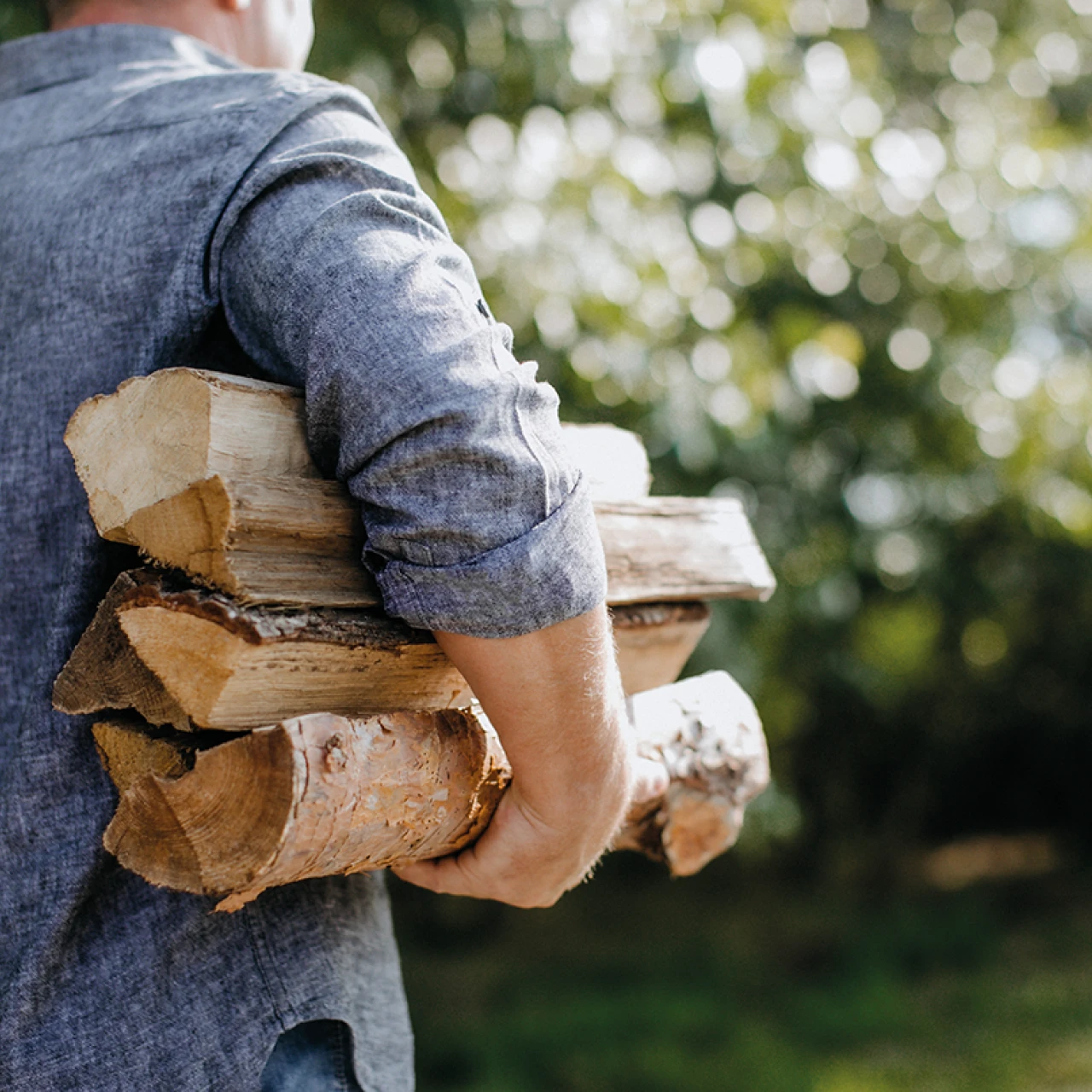 Holzscheite tragen | © KWB, LupiSpuma Ein Mann trägt in den Armen Stückholz