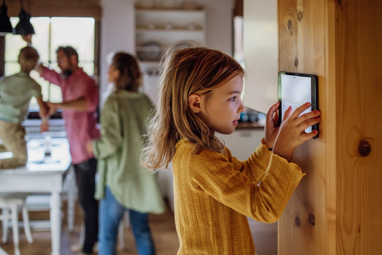 © KWB, Halfpoint Maedchen bedient Smart-Home-Display zur Temperatureinstellung im Haus.