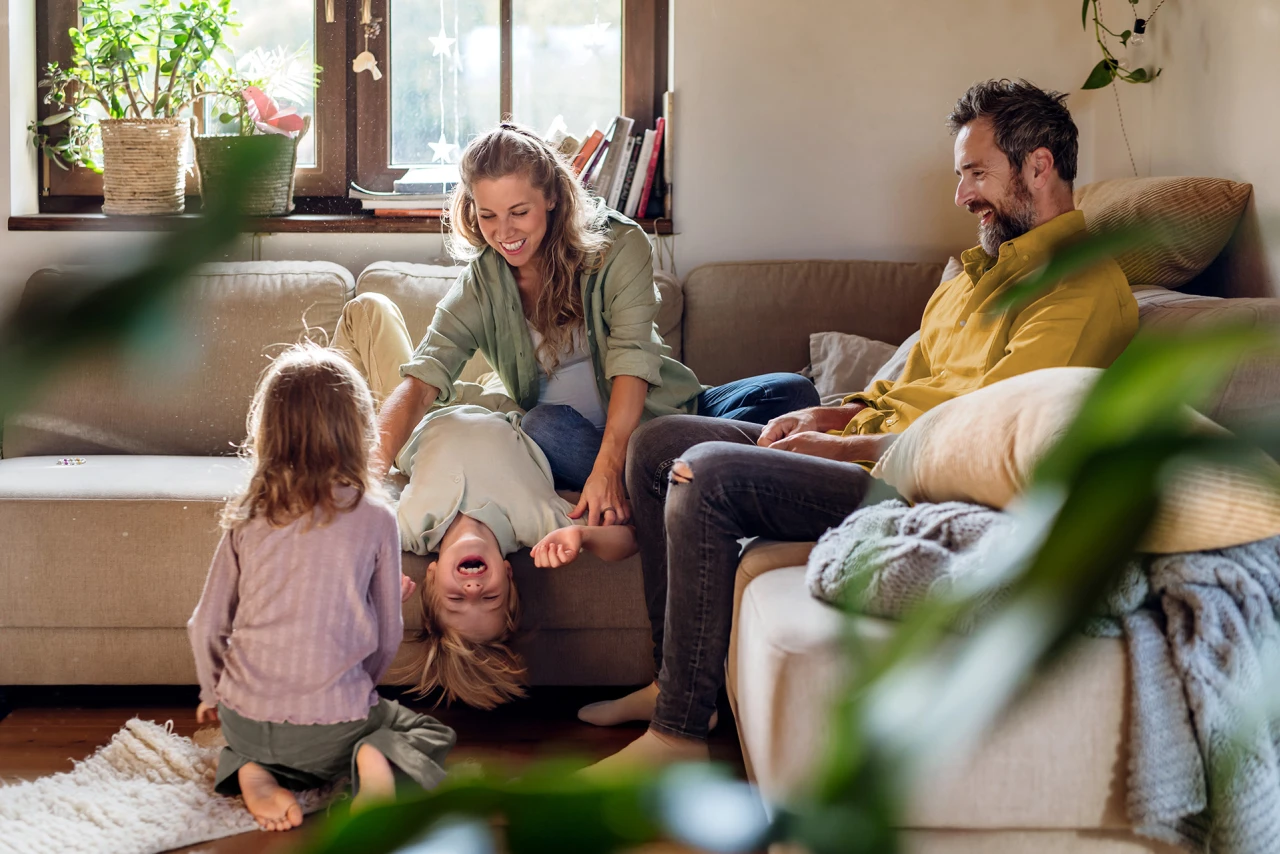 Familienzeit | © KWB, Halfpoint Eine fröhliche Familie sitzt im Wohnzimmer auf dem Sofa.