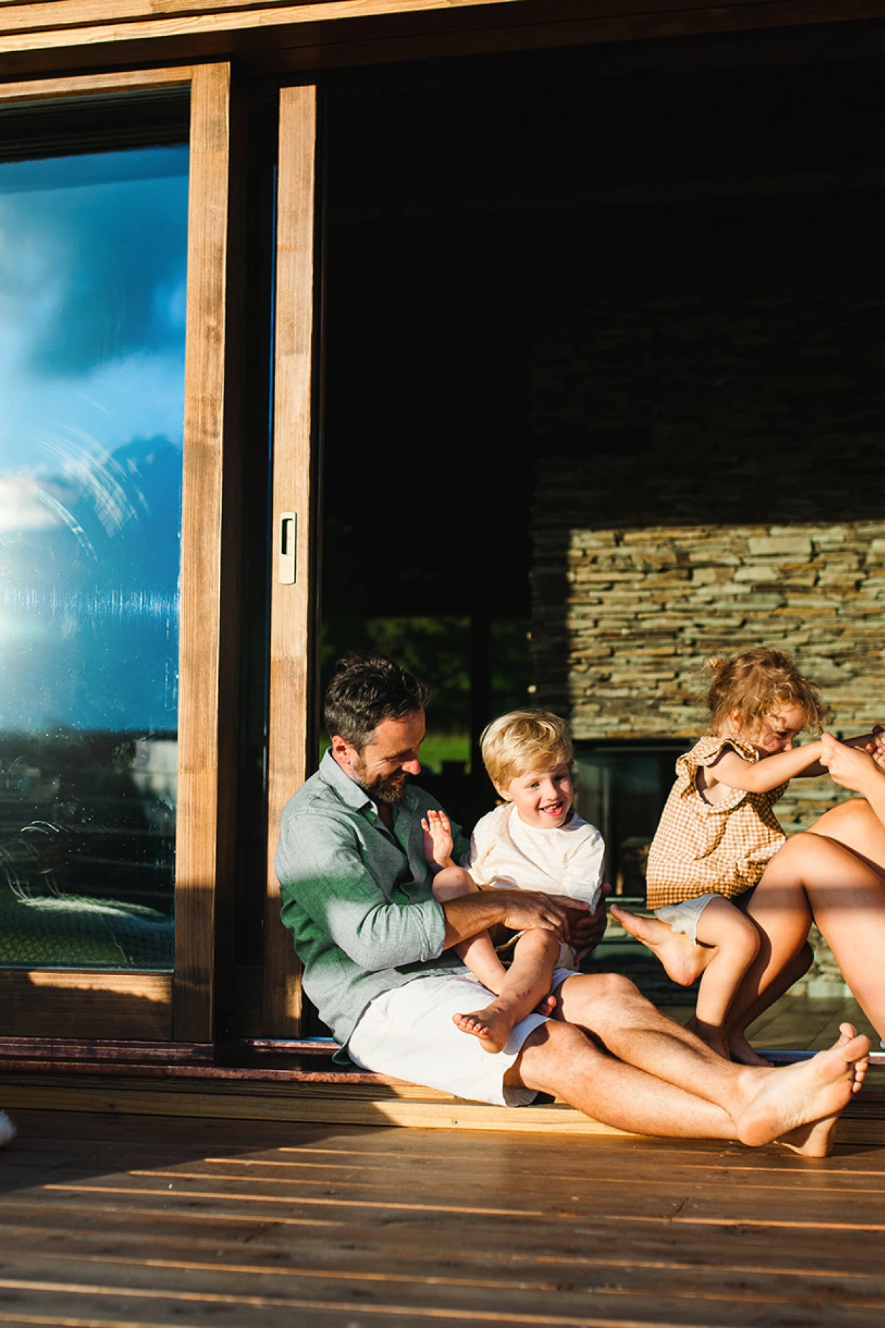 Familienzeit | © KWB, Halfpoint Familie sitzt lachend auf der Terrasse vor dem Haus und genießt die Sonne.