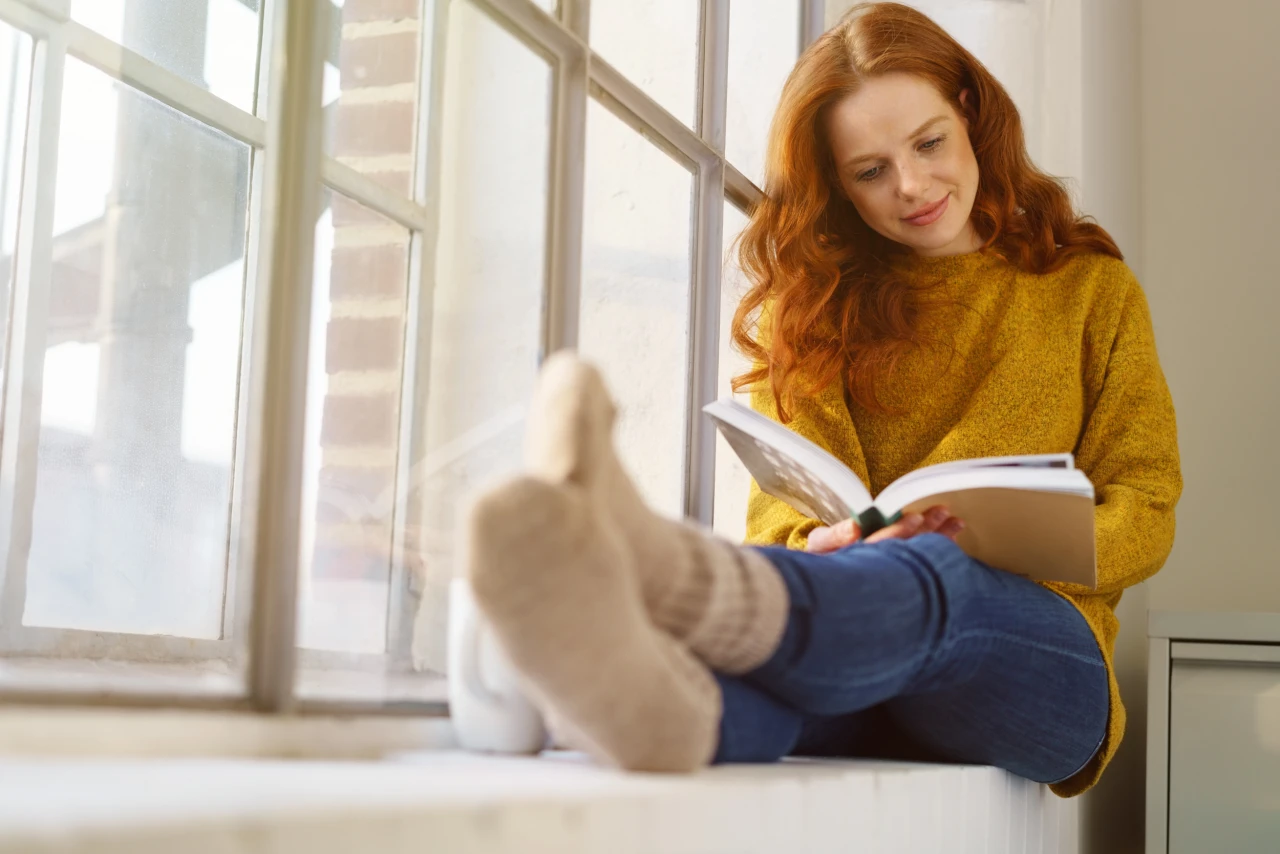 Lesende Frau | © KWB Frau liest ein Buch auf dem Fensterbrett