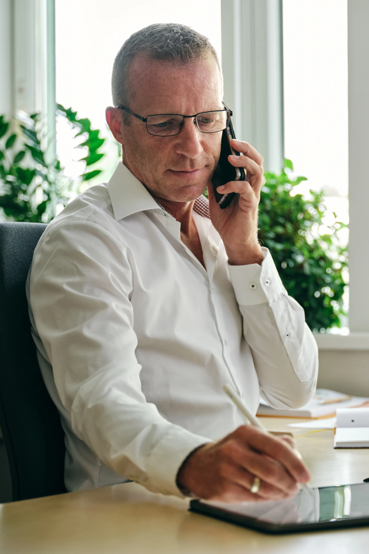 ein Mann telefoniert und macht Notizen | © KWB, Raphael Nast Ein Mann telefoniert im Buero und macht sich Notizen auf seinem Tablet