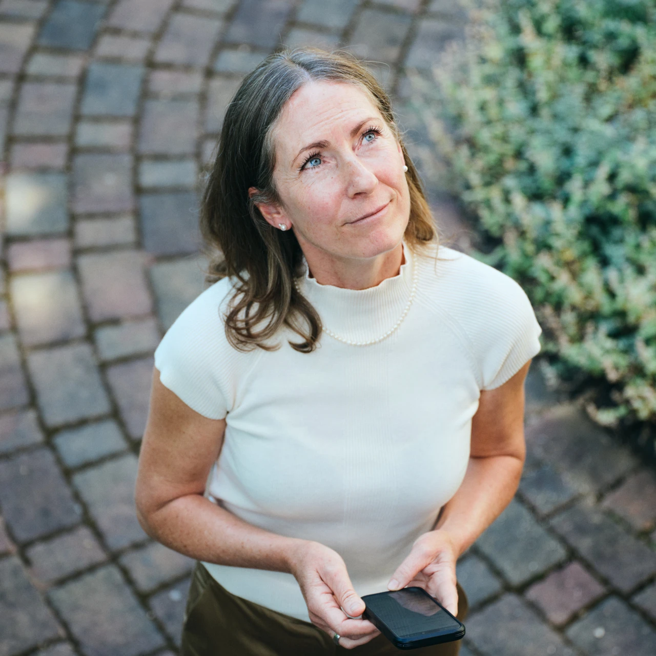 Referenzkunde Antje Krause | © KWB, Raphael Nast Man sieht eine Frau die ein Handy in der Hand haltet und in die ferne sieht