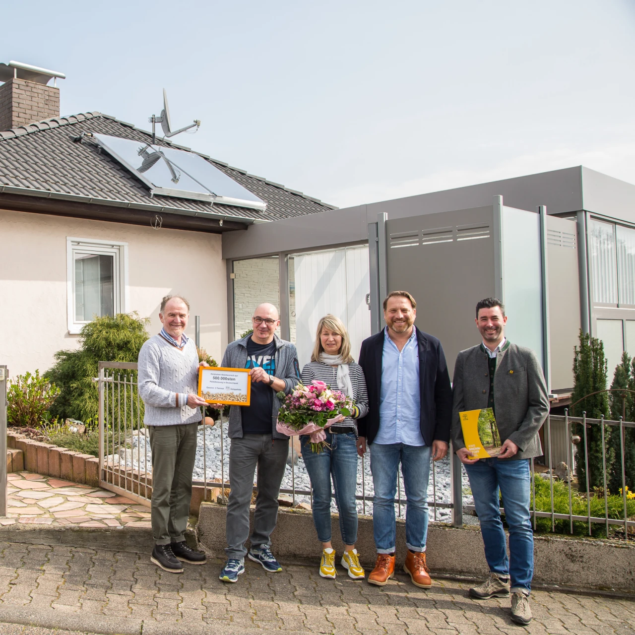 Referenzkunde Familie Haedrich | © KWB, DEPI Hier sieht man die Familie Hadrich vor Ihrem Haus mit der Auszeichnung fuer die 500000 Pelletanlage