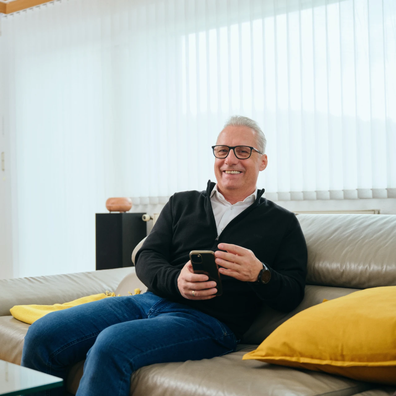 Referenzkunde Martiner | © KWB, Raphael Nast Hier sieht man Herrn Nast auf seinem Sofa und er haelt sein Handy