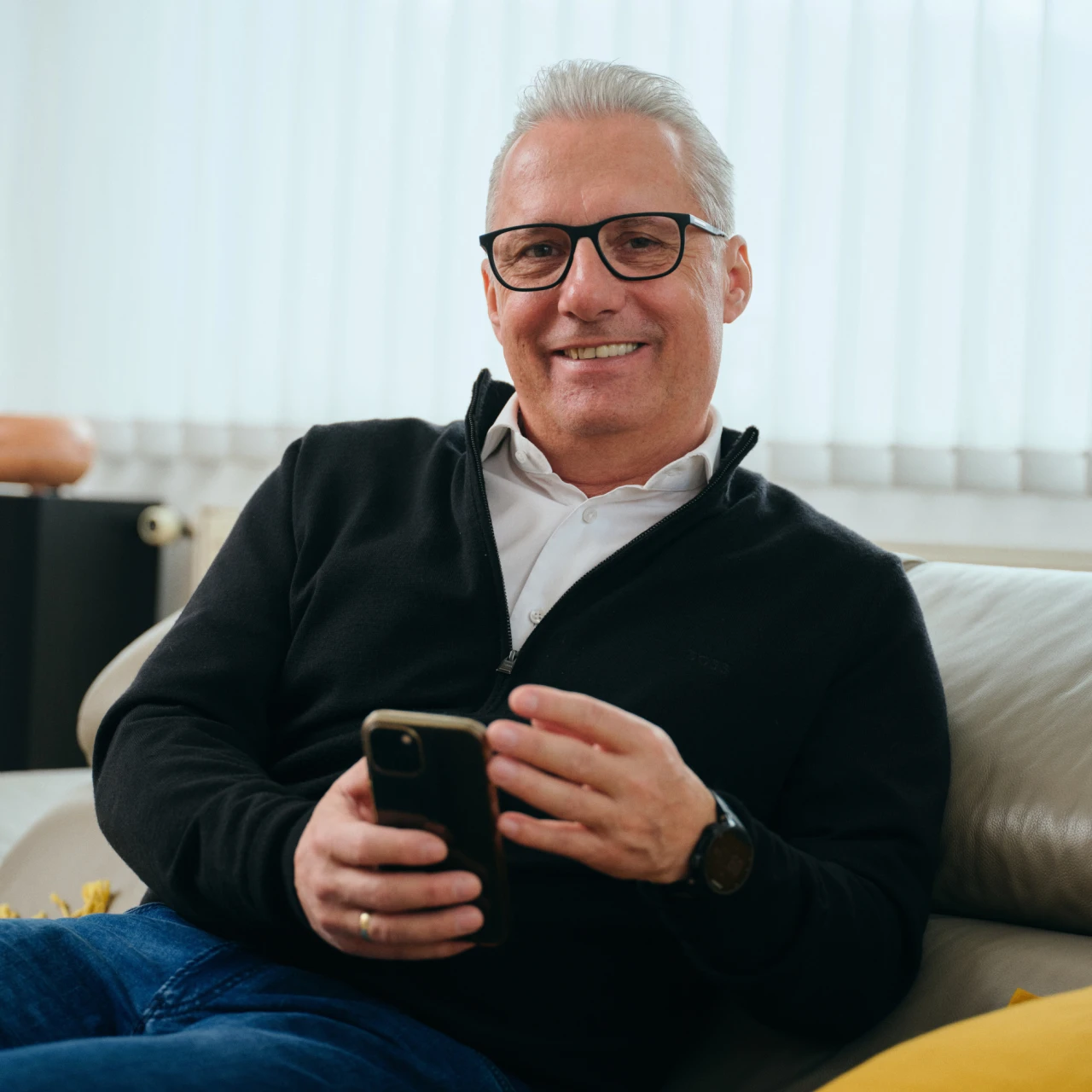 Referenzkunde Martiner | © KWB, Raphael Nast Hier sieht man Herrn Nast auf seinem Sofa und er haelt sein Handy