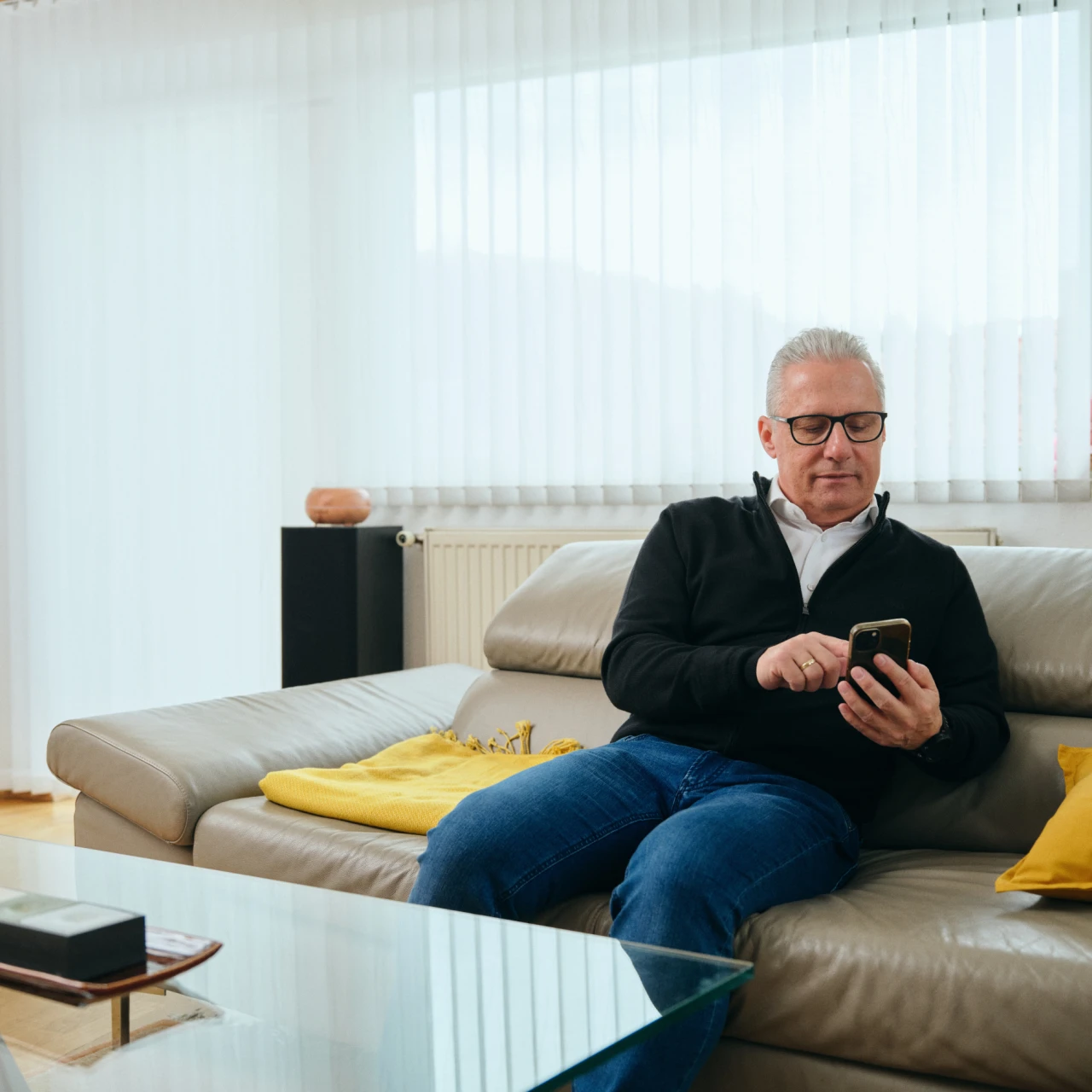Referenzkunde Martiner | © KWB, Raphael Nast Hier sieht man Herrn Nast auf seinem Sofa und er haelt sein Handy