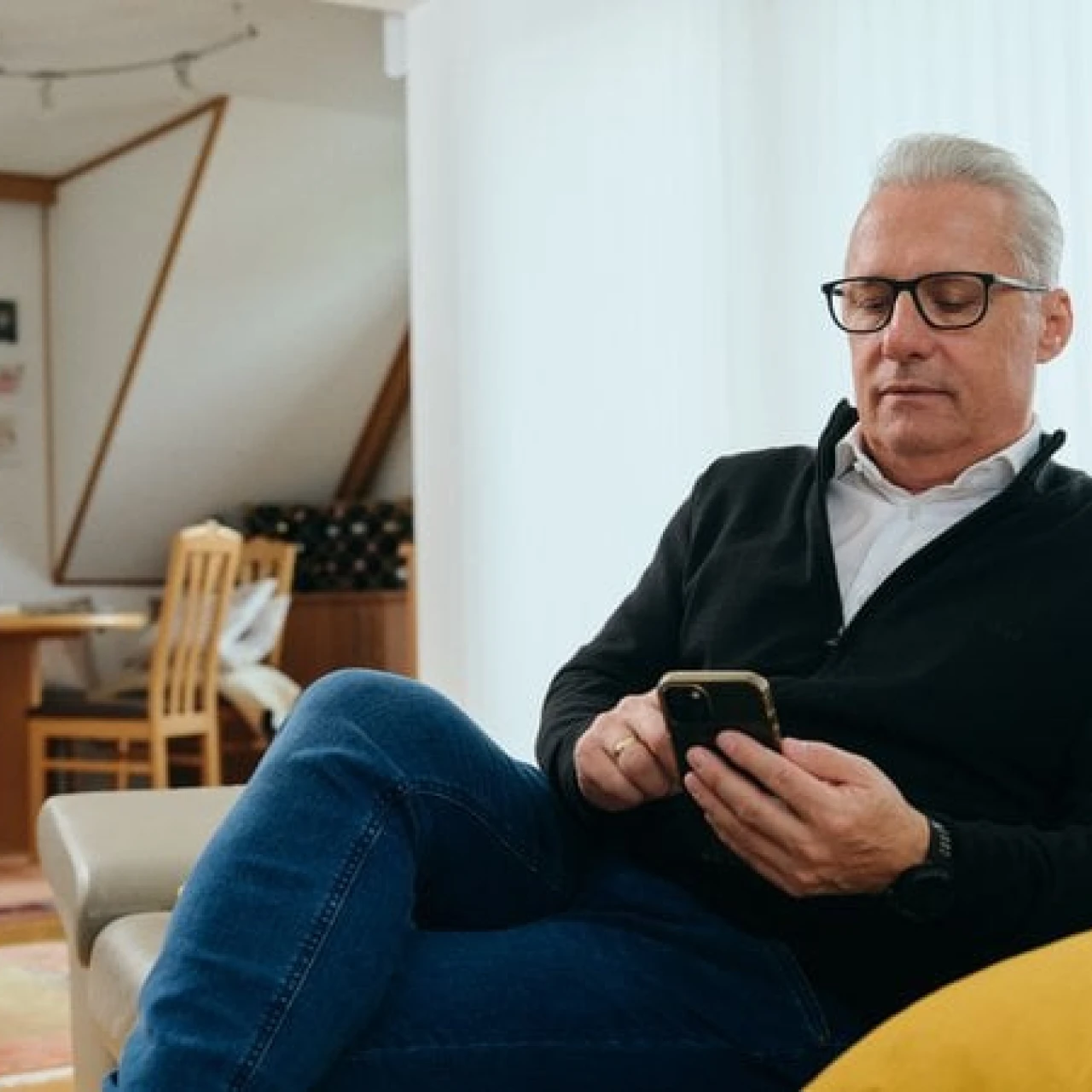 Referenzkunde Martiner | © KWB, Raphael Nast Hier sieht man Herrn Nast auf seinem Sofa und er haelt sein Handy