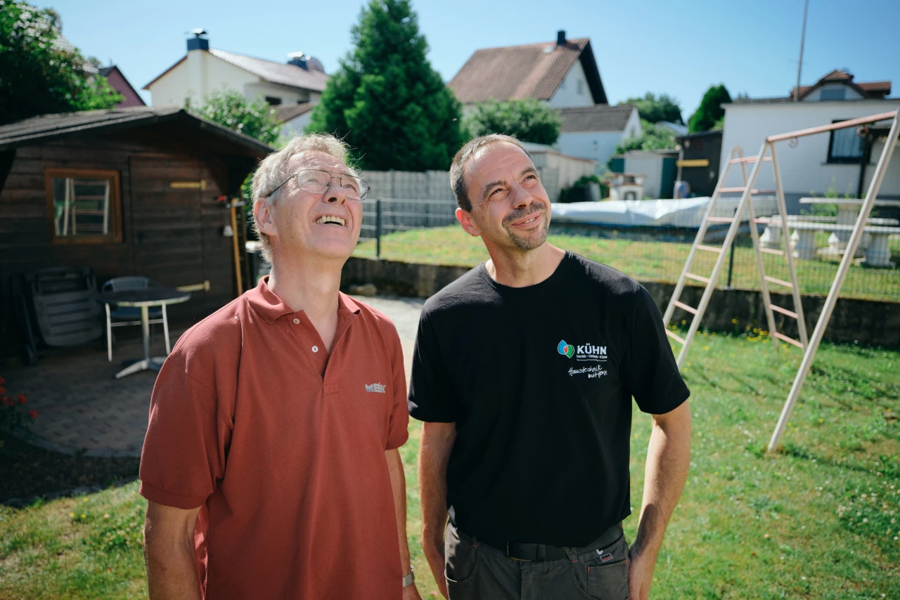 Referenzkunde SHK Kühn | © KWB, Raphael Nast Ein Mitarbeiter von Kuehn und ein Kunde stehen im Garten und schauen nach oben