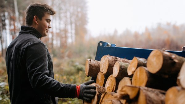 Helmut Strauß im Wald vor einem Holzstapel.